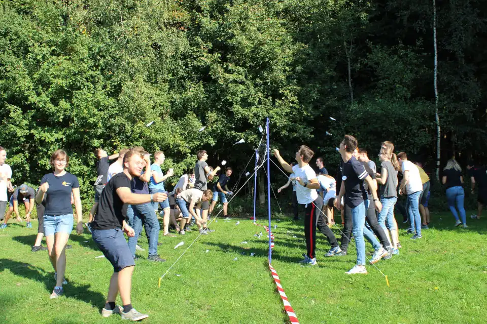 Teilnehmer werfen Papierflieger über ein Volleyball-Netz