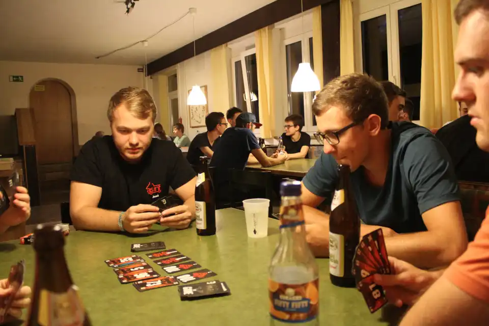 Leute an einem Tisch unterhalten sich und spielen Karten